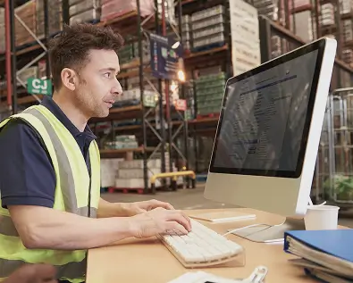 Travailleur devant un ordinateur en entrepôt.